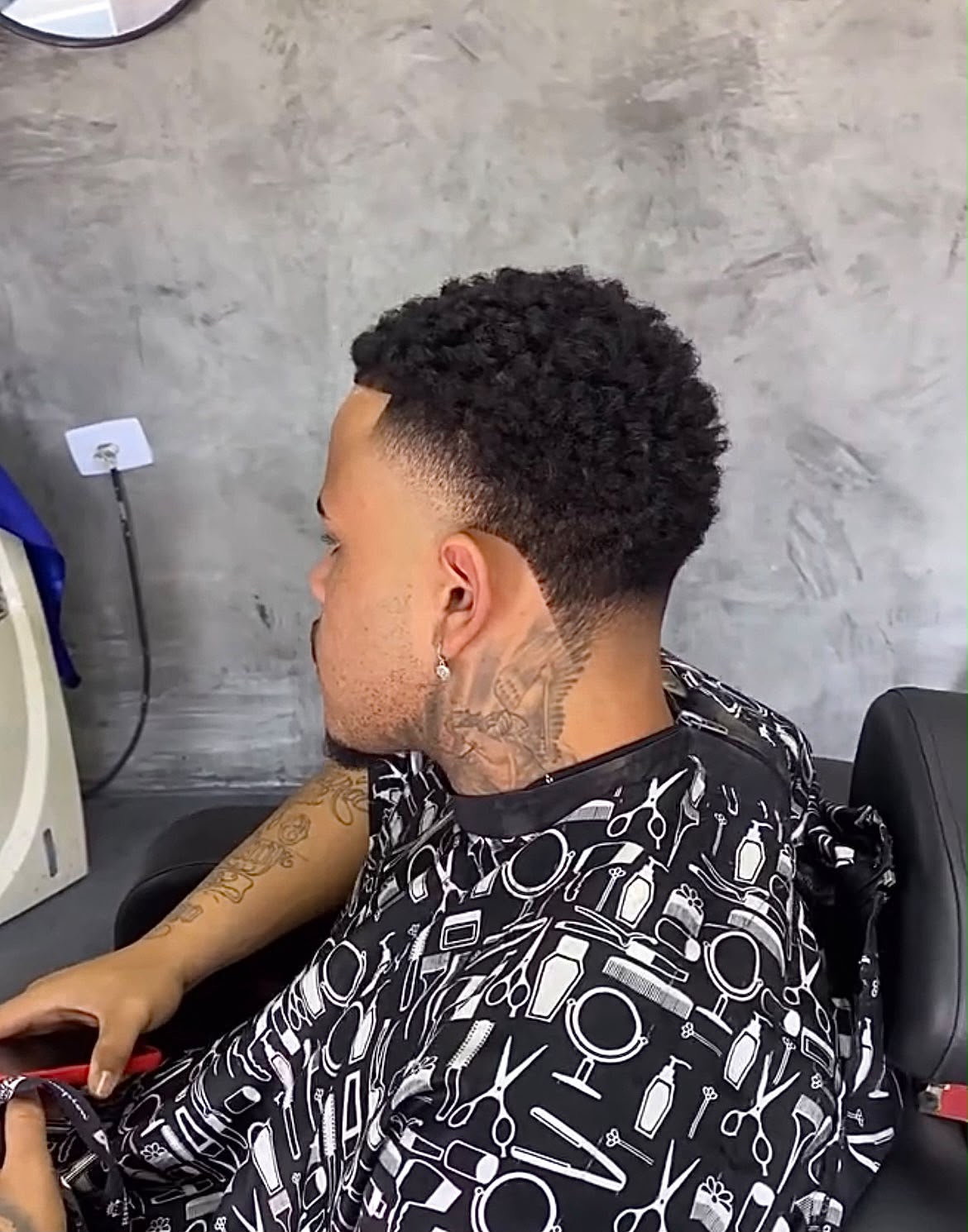 Cabelo cacheado com degradê e tatuagem no pescoço